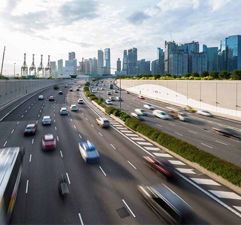 Busy highway with moving cars and a city skyline in the background.