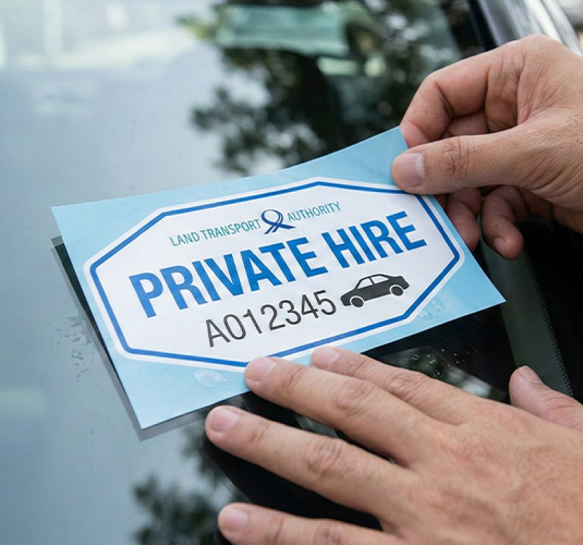 Hands placing a Land Transport Authority Private Hire decal.